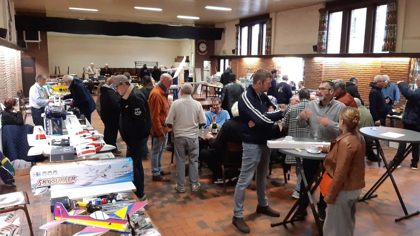 Volle zaal met tafels vol modelvliegtuigen tijdens de tweedehandsbeurs