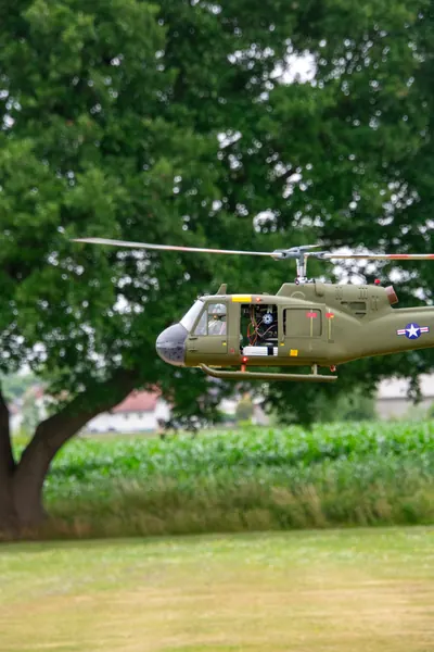 Camouflage-helikopter geparkeerd onder de bomen
